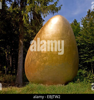 sculpture 'Was war zuerst?' ('What came first?') which shows a giant golden egg at the Waldskulpturenweg, Germany, North Rhine-Westphalia, Siegerland, Bad Berleburg Stock Photo