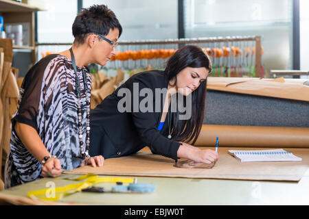 Two seamstresses drawing dressmakers pattern in workshop Stock Photo