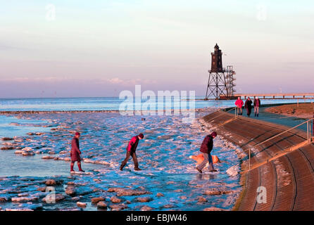 people in frozen wadden sea and lighthouse Obereversand, Germany, Lower Saxony, Dorum-Neufeld Stock Photo