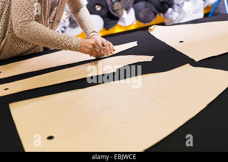 Hands of mature seamstress chalking shape onto textile on work table Stock Photo