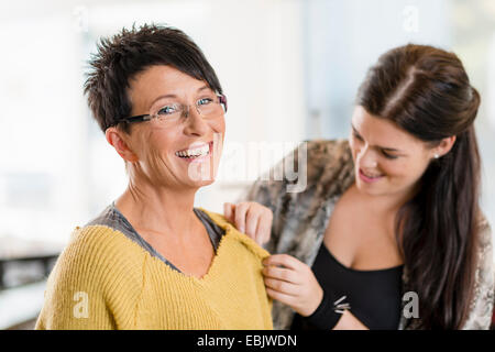 Young seamstress pinning shoulder of customers sweater in workshop
