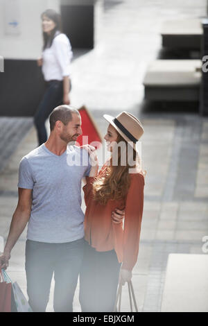Couple in shopping mall, standing face to face, holding shopping bags Stock Photo