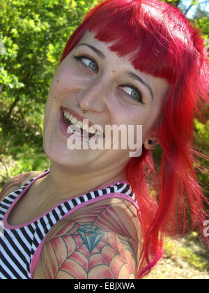 young tattooed redheaded woman laughing and looking over her shoulder Stock Photo