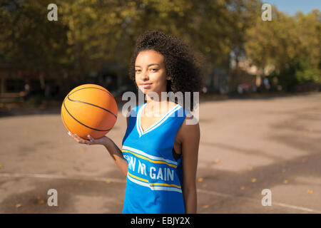 Portrait young female basketball player holding up basketball Stock Photo