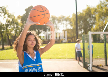 Young female basketball player holding up basketball Stock Photo