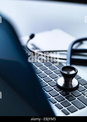 Stethoscope on top of laptop computer keyboard on doctors desk Stock Photo