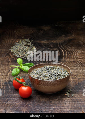 Still life with vine tomatoes, fresh basil and bowl of puy lentils Stock Photo