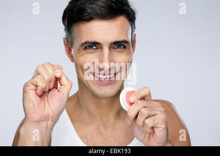 Portrait of a happy man with dental floss over gray background Stock Photo