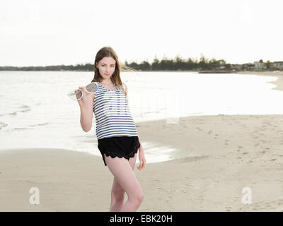 Young woman holding oversize sunglasses on beach Stock Photo