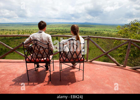 a young couple sitting on balcony and admiring the view to Tarangire National Park, Tanzania, Tarangire National Park Stock Photo