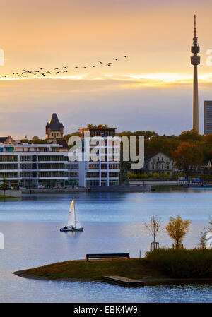 sailing boat on Lake Phoenix in front of the Hoerder Burg and the television tower Florian at sunset, Germany, North Rhine-Westphalia, Ruhr Area, Dortmund Stock Photo