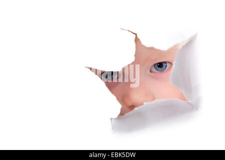 little boy looking through hole in a white paper surface Stock Photo