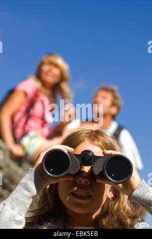 familiy on a mountain trail, girl looking through a field glass, France Stock Photo