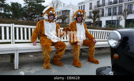 two men in Easter bunny costumes taking a break sitting on a bench with the masks opened, Germany, Mecklenburg-Western Pomerania, Ruegen, Binz Stock Photo