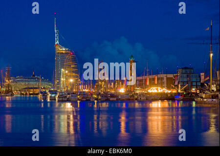 tall ships in harbour at night, lighthouse, hotel Atlantic and Klimahaus in background, Germany, Bremerhaven Stock Photo