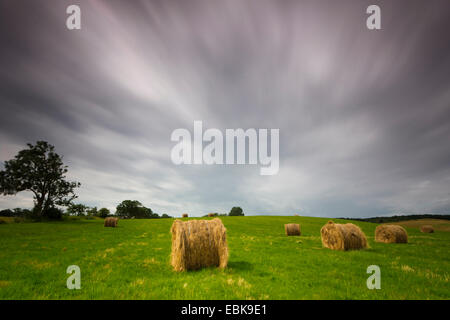 haybales in a meadow under moving thunderclouds, long exposure, Germany, Mecklenburg-Western Pomerania, Hiddensee, Dornbusch Stock Photo