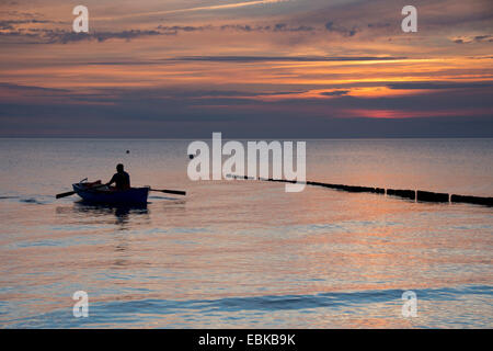 man in fishing boat rowing to the beach in evening light, Germany, Mecklenburg-Western Pomerania, Hiddensee Stock Photo