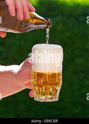 fresh beer from a beer bottle is poured into beer glass Stock Photo