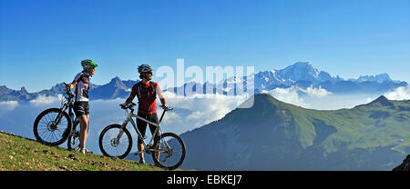 two mountain biker standing on mountain meadow and enjoying the mountain scenery, France, Savoie, La Plagne Stock Photo