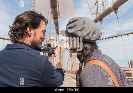 USA, New York State, New York City, Brooklyn, Happy couple photographing Brooklyn Bridge with digital camera Stock Photo