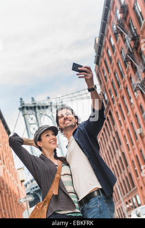 USA, New York State, New York City, Brooklyn, Couple taking selfie on street, Brooklyn Bridge in background Stock Photo