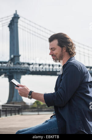 USA, New York State, New York City, Brooklyn, Man using tablet pc, Manhattan Bridge in background Stock Photo