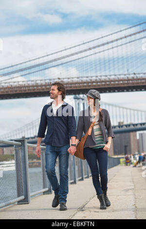 USA, New York State, New York City, Brooklyn, Couple walking on promenade, Brooklyn Bridge in background Stock Photo