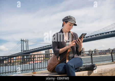 USA, New York State, New York City, Brooklyn, Woman using tablet pc, Manhattan Bridge in background Stock Photo