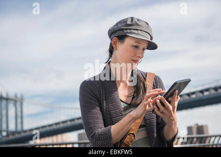 USA, New York State, New York City, Brooklyn, Woman using tablet pc, Manhattan Bridge in background Stock Photo