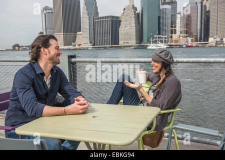 USA, New York State, New York City, Brooklyn, Happy couple sitting and discussing with cityscape in background
