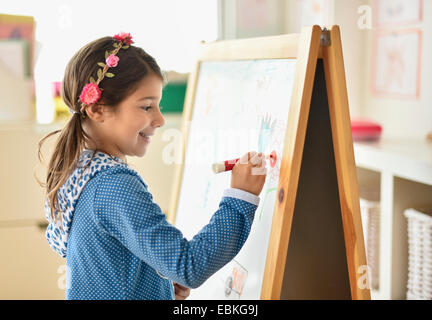 Girl (6-7) writing on board in classroom Stock Photo