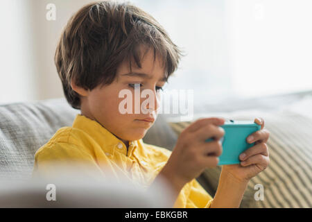 Boy (6-7) sitting on sofa and using cell phone Stock Photo