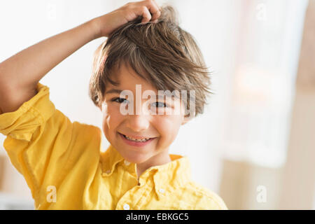 Portrait of smiling boy (6-7) with hand in hair Stock Photo