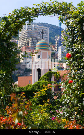 rose arch in a garden enframing a steeple, France, Monaco Stock Photo