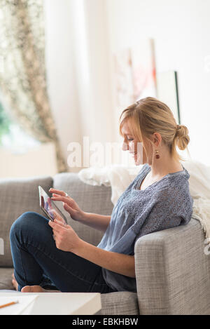 Smiling woman sitting on sofa with tablet pc Stock Photo