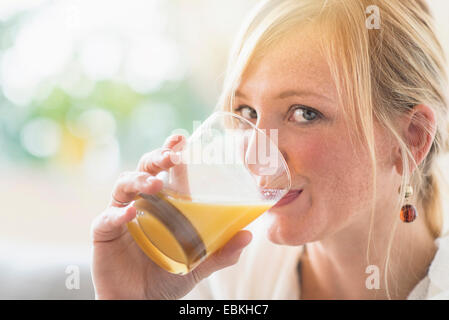 Woman sitting in living room and drinking orange juice Stock Photo