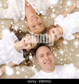 parents and two girls lying on floor at home Stock Photo