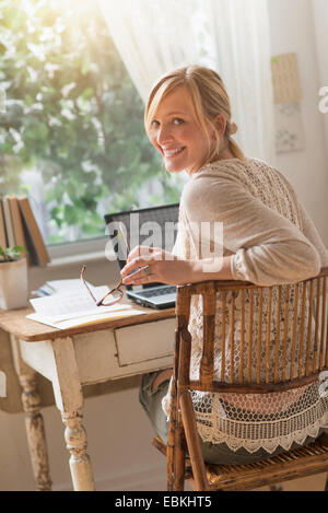 Smiling woman sitting at desk and looking over shoulder Stock Photo
