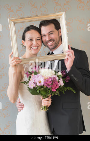 Bride and groom posing with picture frame Stock Photo