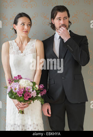 Anxious bride and groom posing with bunch of flowers Stock Photo