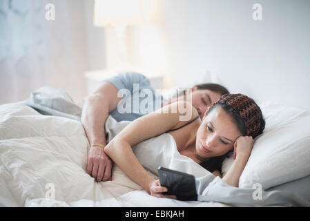 Couple in bed, Man sleeping, Woman using tablet pc Stock Photo