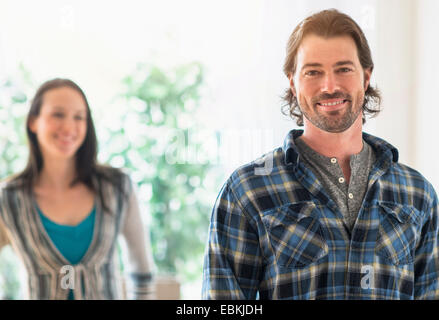 Smiling man looking at camera, woman in background Stock Photo