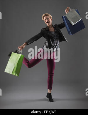 Studio shot of cheerful woman holding shopping bags Stock Photo