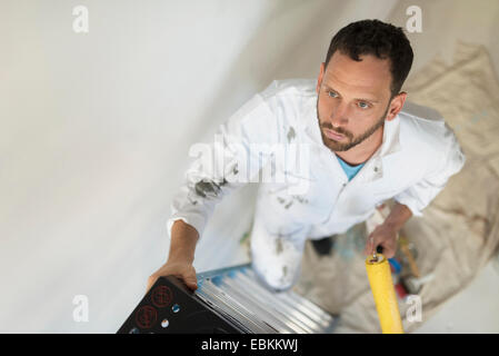 Man climbing ladder with paint roller Stock Photo