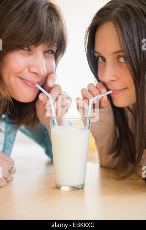 Teenage girl (14-15) drinking milk with her mom at home Stock Photo