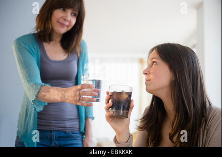 Mom encouraging teenage girl (14-15) to drink mineral water Stock Photo