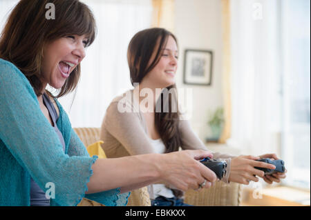 Teenage girl (14-15) playing video games with her mom Stock Photo