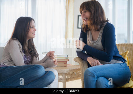 Teenage girl (14-15) talking with her mom in living room Stock Photo