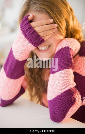 Girl (12-13) grinning and covering eyes Stock Photo