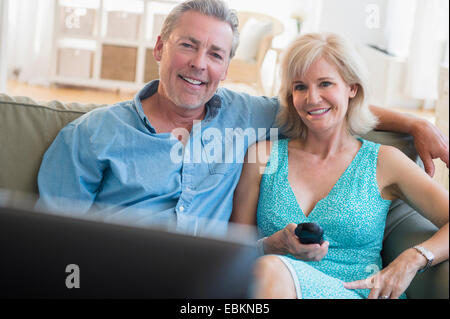 Portrait of couple sitting on sofa watching TV Stock Photo